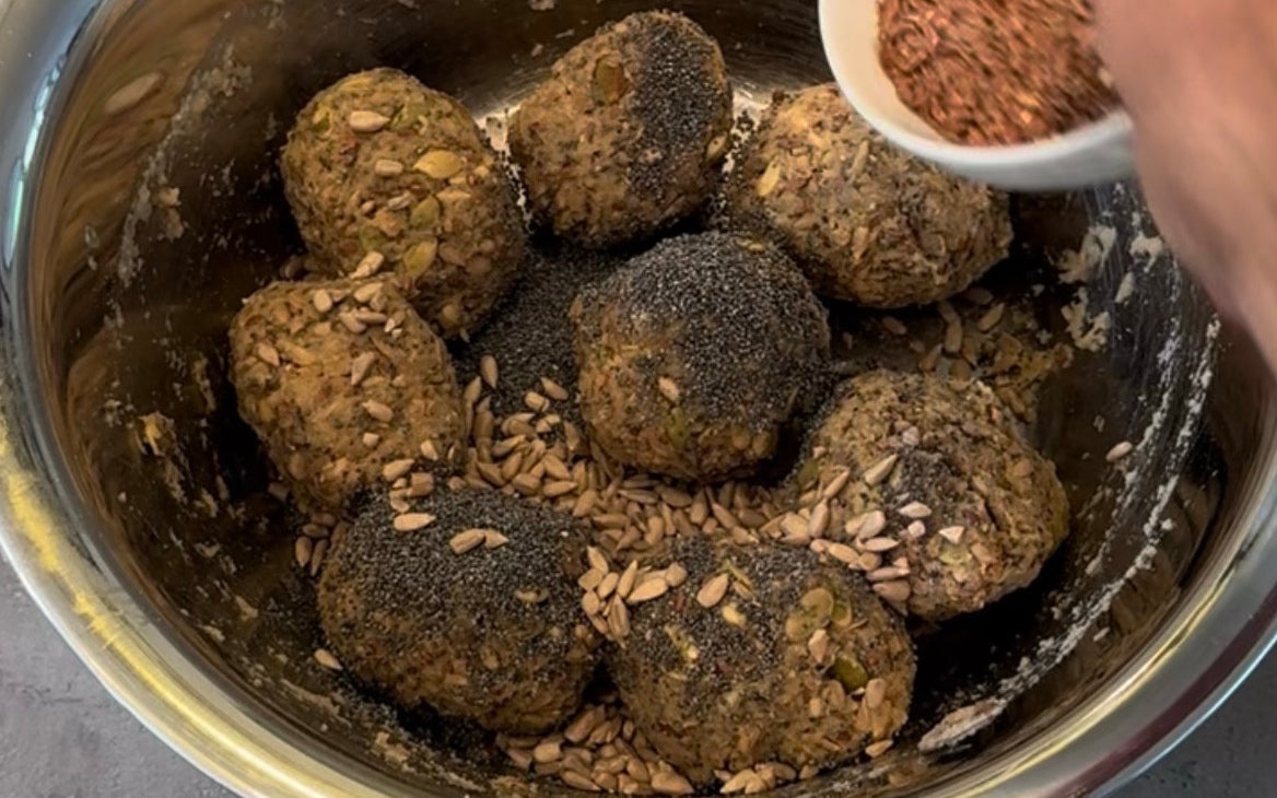 Acht bereits geformte rohe BROT OHNE Brötchen in einer Schüssel, mit Saaten bestreut